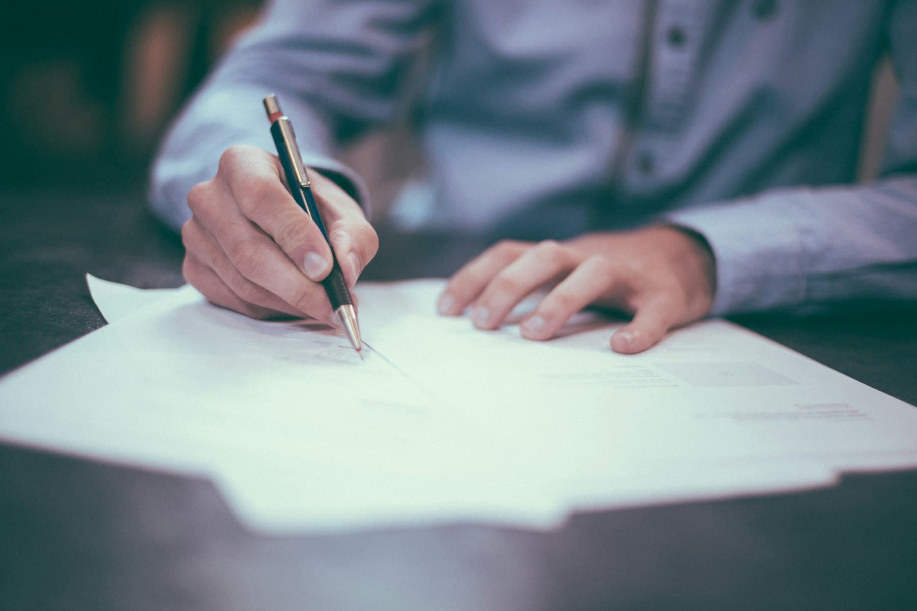 A hand signing a document
